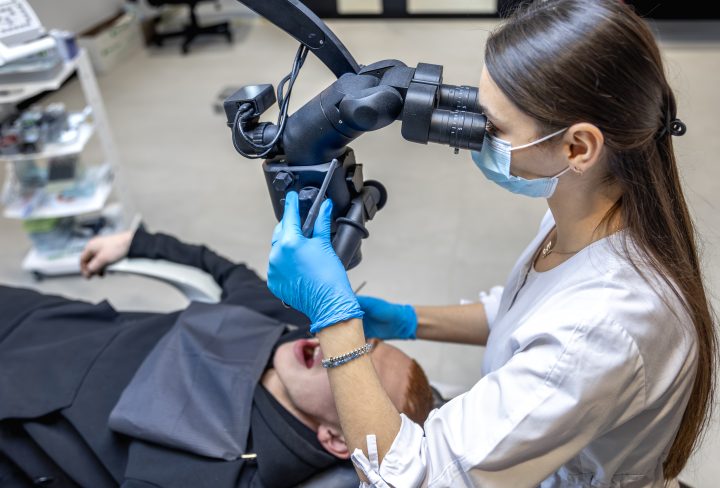 Young female dentist treating patient's teeth with dental microscope. Dentistry concept. High quality photo. Professional dental treatment. Dental equipment. SSUCv3H4sIAAAAAAAAA41Py46DMAz8F5+DFKCoKb9S7SEQQ60CqRKz1Qrl3+tQql43p3nEnvEG5KAFbbEcjNPF0DWmKEscCuOqcyFiU5/NxWBVgwJnGaEt69o0l1Ola3PSjZanoLORemg3oGlaIwfL5BdoxQm4OAw7REfsA9lJWFIQ2fIaMcqYsF52j+Lu/LPvumVdCkp4XLsMkvqn9qPAjrj0f3l/ykUmtHvcVaz7kzHMR7bnW66Y4SNQT8t4dJJT/PzGi+c8uyew7+/kjuH3GTcSNeQsWB+Ttw7dYa/dTMwfGvCX8Pn9nVJ6AYpTlPiEAQAA